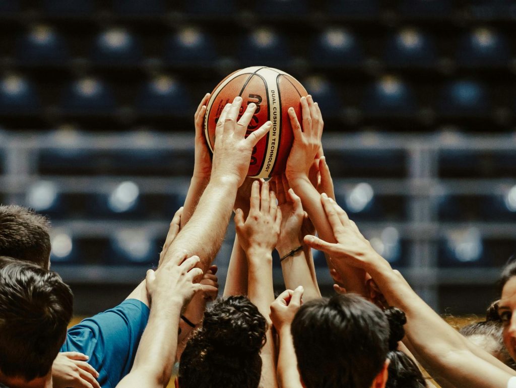 A group of people reaching for a basketball